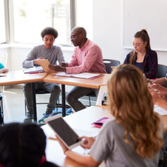 High,School,Teacher,With,Pupils,Using,Digital,Tablets,In,Technology